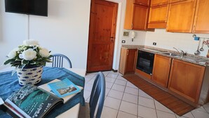 A kitchen with wooden cabinets, a built-in dishwasher, and a dining area with a table set for two.