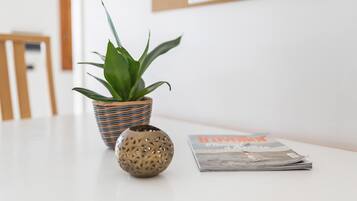 Een plant in een geweven pot, een decoratieve bol en een tijdschrift op een witte tafel.