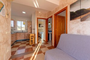Ein Zimmer mit Schachbrettboden, einer Couch, einem Holzschrank und einem Bett mit Stadtbildgemälde.