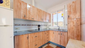 Een keuken met houten kastjes, een granieten aanrechtblad, een spoelbak en een raam met uitzicht.