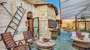 Un espace extérieur aménagé dans un style rustique, avec des chaises en bois, une table ronde et un mur en pierre.