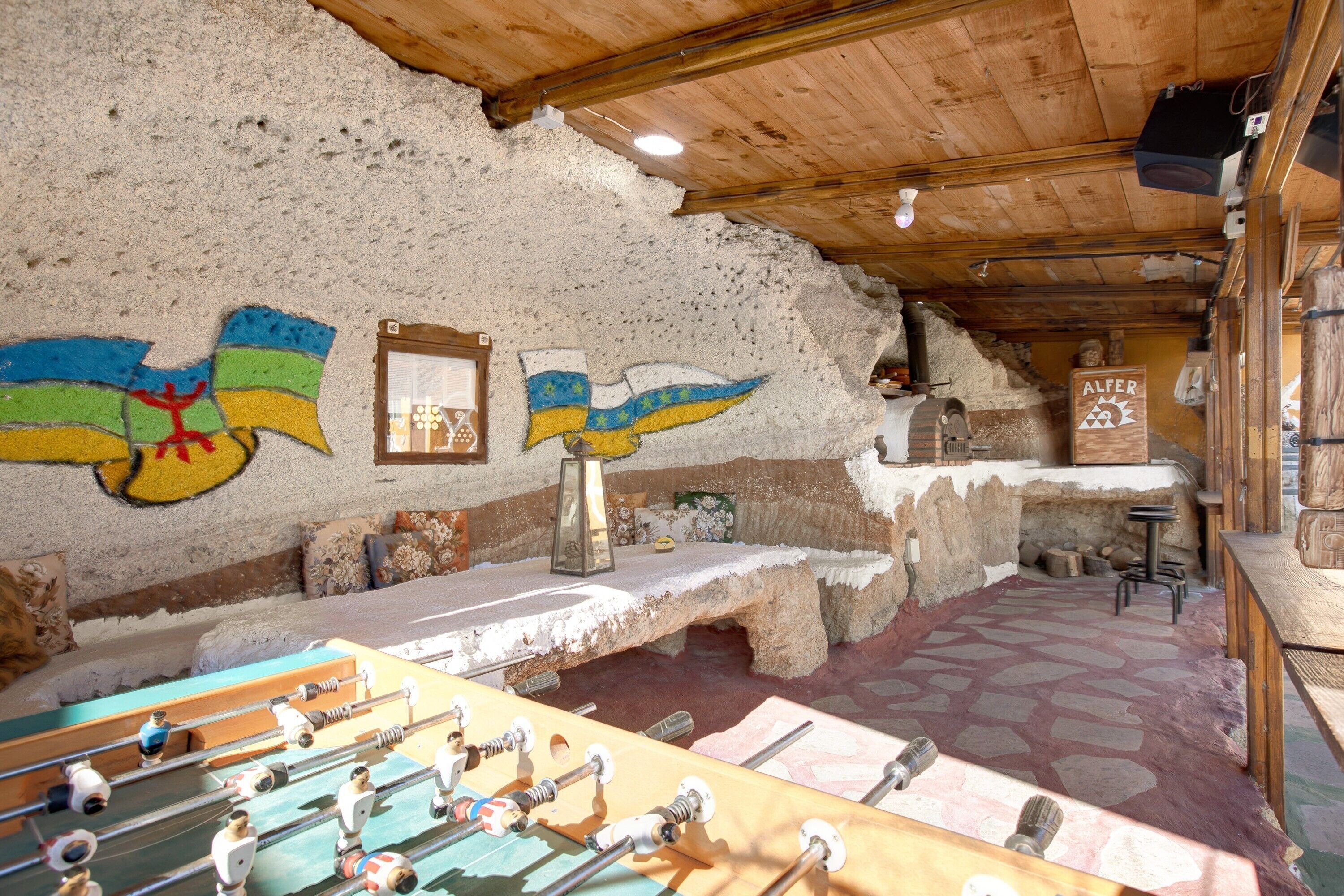 A rustic interior with a foosball table, stone walls, and a wooden ceiling.