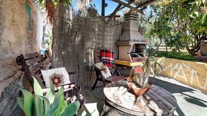Un espace extérieur rustique aménagé avec une table ronde en bois, un banc et un barbecue.