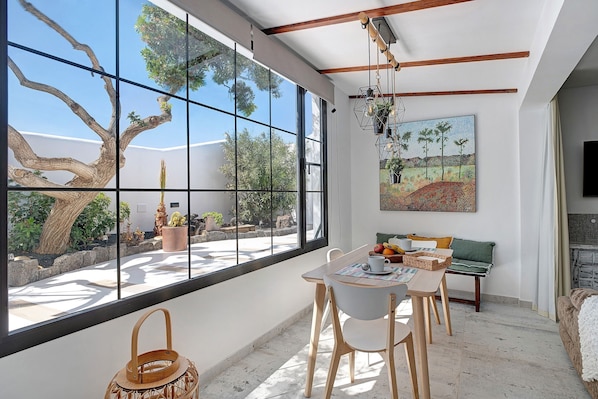 Un intérieur moderne avec de grandes fenêtres, un coin repas et un tableau.