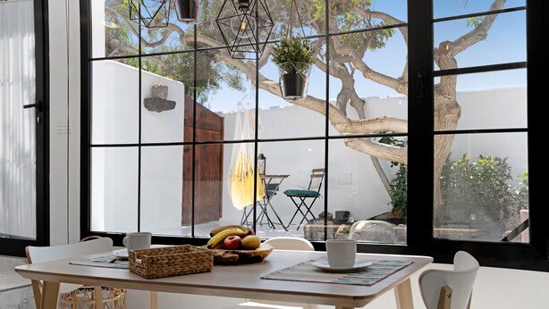 Un comedor con una mesa dispuesta para dos personas, una cesta de mimbre y un frutero.