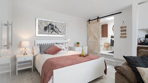 Un dormitorio moderno con cama, mesitas de noche, una planta pequeña y una obra de arte en la pared.
