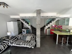 A modern kitchen with a microwave, kettle, and bar stools. There is a staircase leading to a second floor. - Duplex Bungalow with 2 Bedrooms and 2 Private Bathrooms in Maspalomas (San Bartolome de Tirajana)