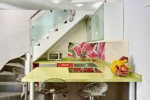 Une cuisine équipée d’un four à micro-ondes, d’un panier de fruits et d’un escalier.