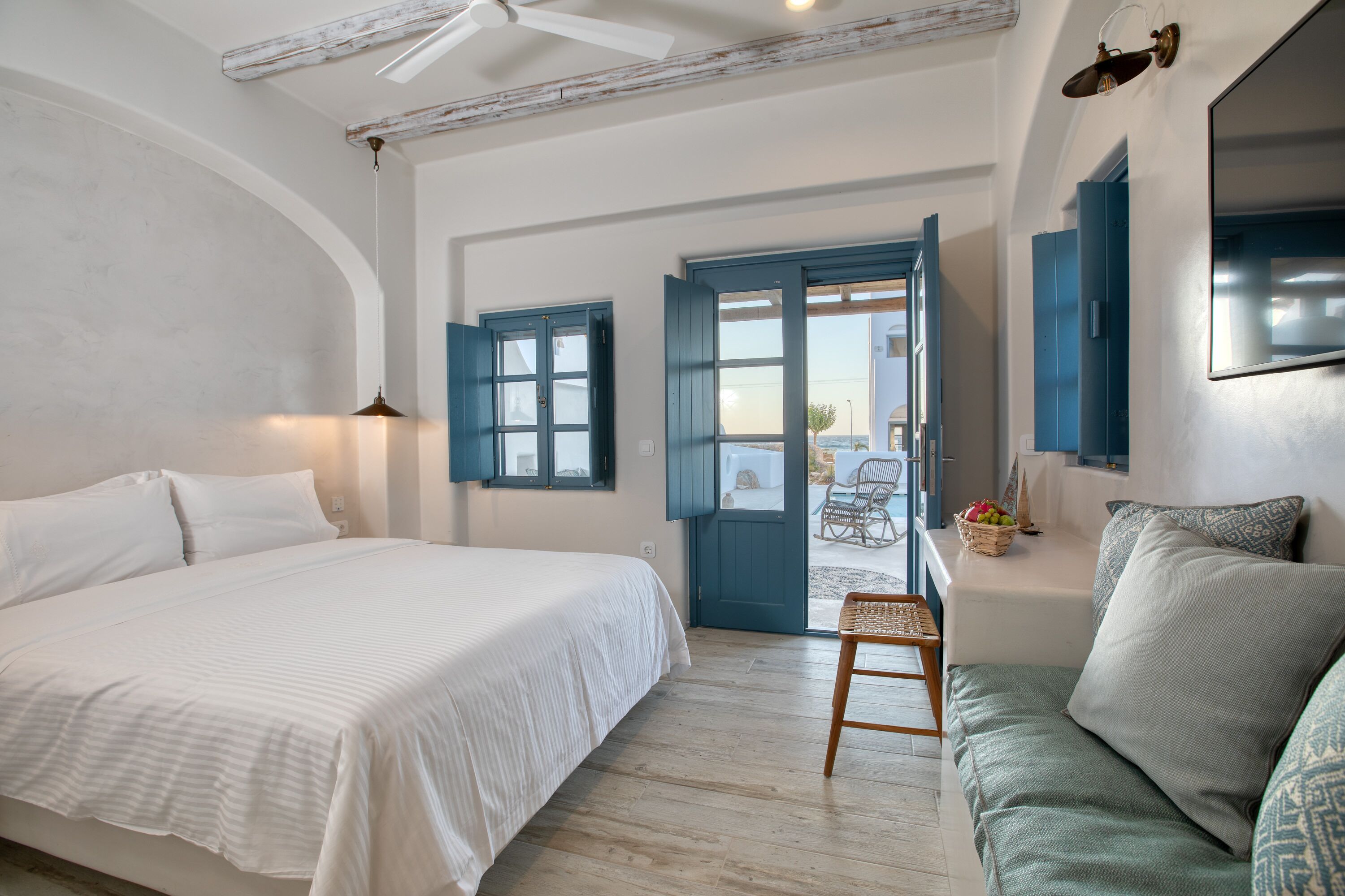 Un dormitorio con cama, suelo de madera, ventilador de techo y vistas al exterior.