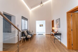 A modern interior with a staircase, a sofa set, a desk, and a door leading to another room.