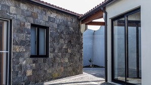 Ein Gebäude aus Stein mit einem Ziegeldach, einer großen Glasdoor und einem kleinen Fenster.