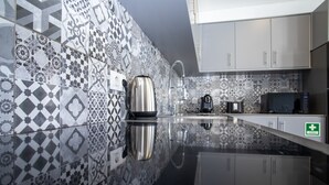 Eine moderne Küche mit gemusterten Fliesen, Edelstahlgeräten und einer glatten, reflektierenden Arbeitsplatte.
