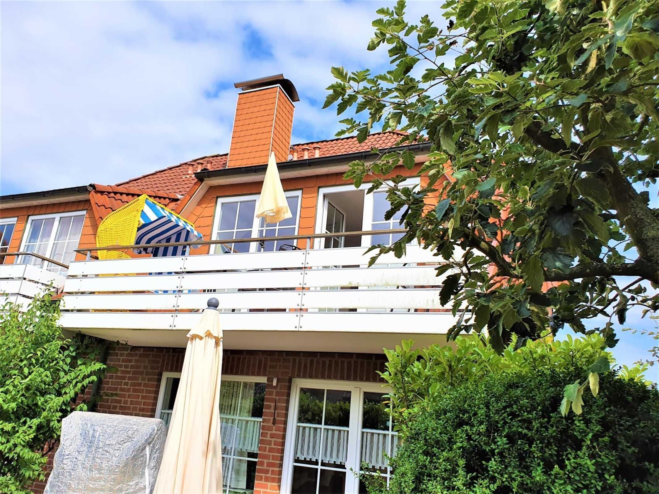 A two-story house with a balcony, a chimney, and a tree in the foreground.