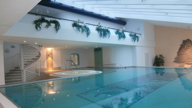 An indoor swimming pool with a glass ceiling, stairs, and decorative plants. - TRA-431 - Residence Trafalgar (Cuxhaven)