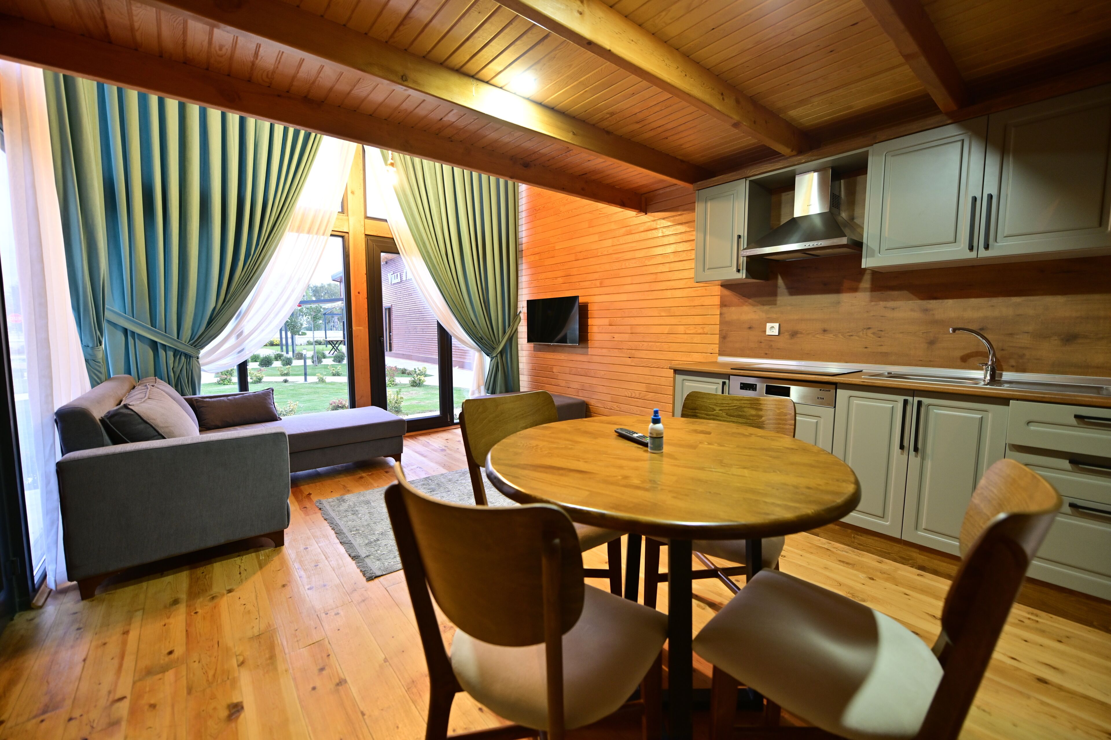 A cozy living area with a wooden ceiling, a round dining table, and a sofa.