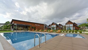 A hotel with a swimming pool, wooden deck, and multiple guest rooms with large windows. - Villa d'Mare (Demre)