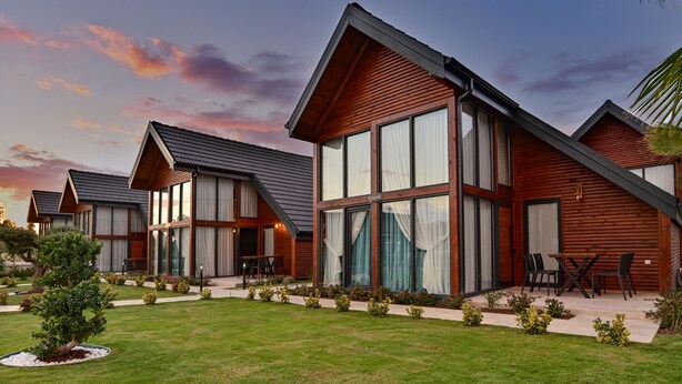 A modern hotel with multiple units, large windows, and a well-maintained lawn. - Villa d'Mare (Demre)