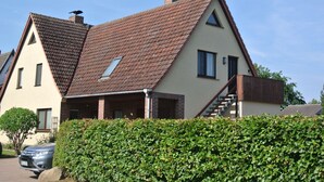 Una casa de dues plantes amb teulada inclinada, una xemenea visible i una escala que condueix al pis superior.