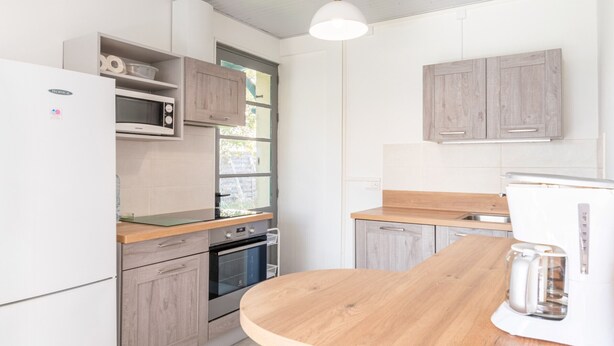 Eine moderne Küche mit Holzschränken, einem eingebauten Backofen, einer Mikrowelle und einer Kaffeemaschine.