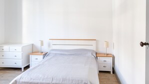 Ein Schlafzimmer mit einem Bett, zwei Nachttischen, einer Nachttischlampe und einer Tür.