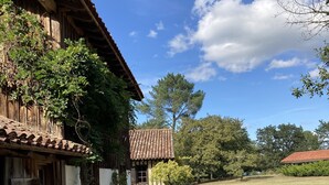 Ein rustikales Gebäude mit Ziegeldach und Holzwänden, umgeben von einem Rasen und Bäumen.