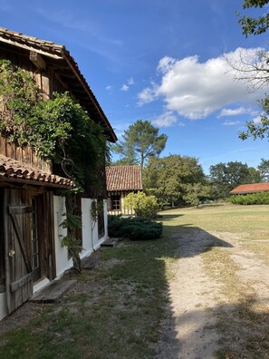 Ein rustikales Gebäude mit Ziegeldach und Holzwänden, umgeben von einem Rasen und Bäumen.