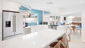 A modern kitchen with white cabinetry, stainless steel appliances, and a large island with bar seating.