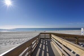 A wooden boardwalk leading to a beach with clear skies and the sun shining. - Phoenix II 2066 | Pools, Hot Tubs, Tennis & more | Oceanfront | My Beach Getaways (Orange Beach)