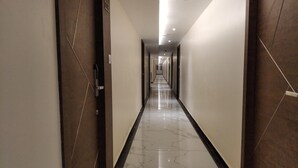 Um corredor comprido e estreito, com chão de mármore brilhante e paredes escuras.