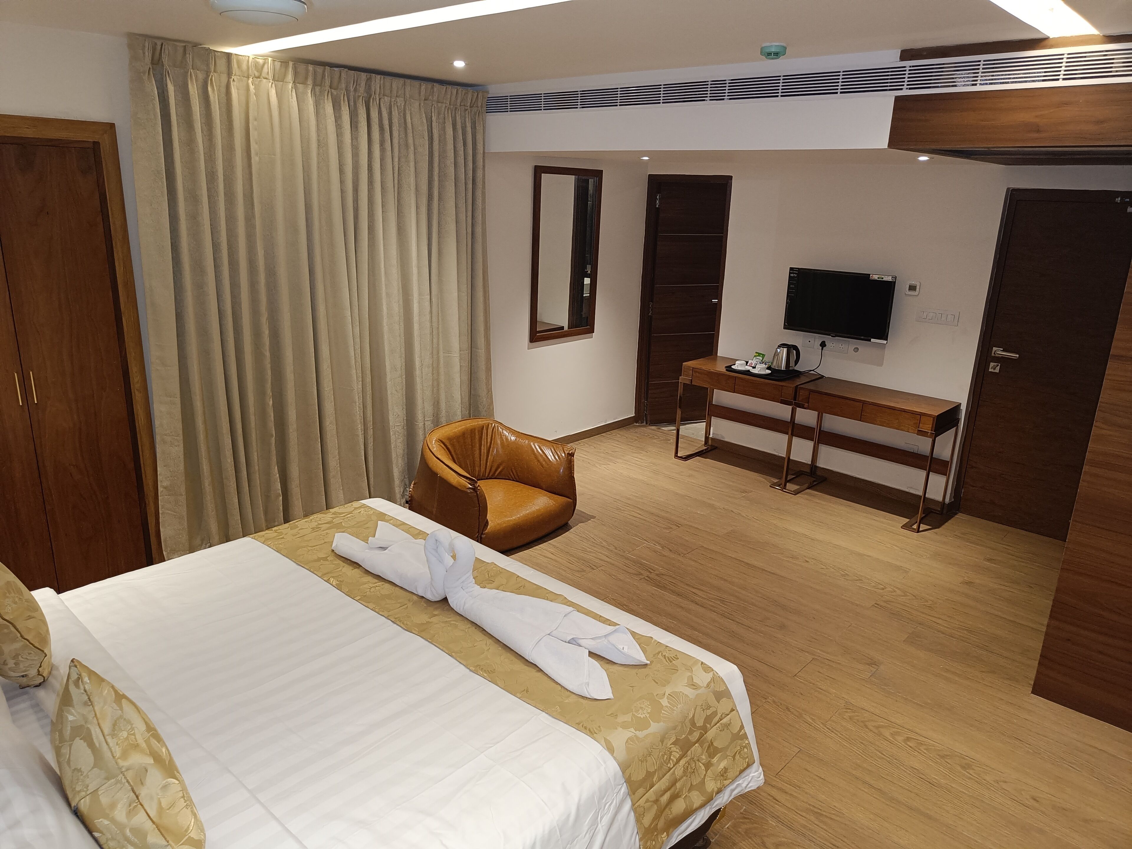 Una habitación de hotel con cama, escritorio, televisor y armario.