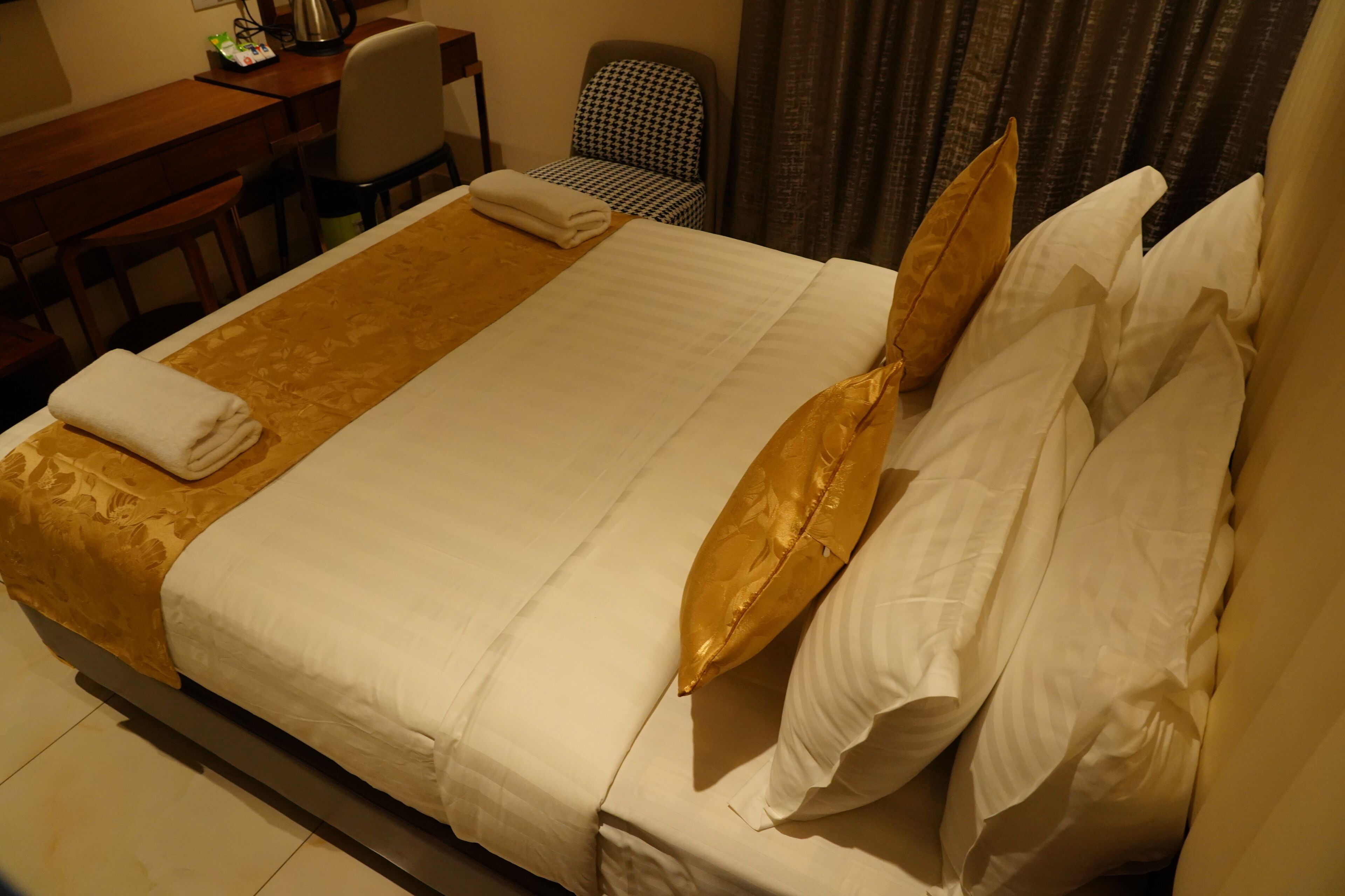 A hotel room with a large bed, a desk, and a chair.