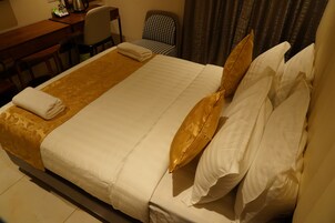 A hotel room with a large bed, a desk, and a chair.