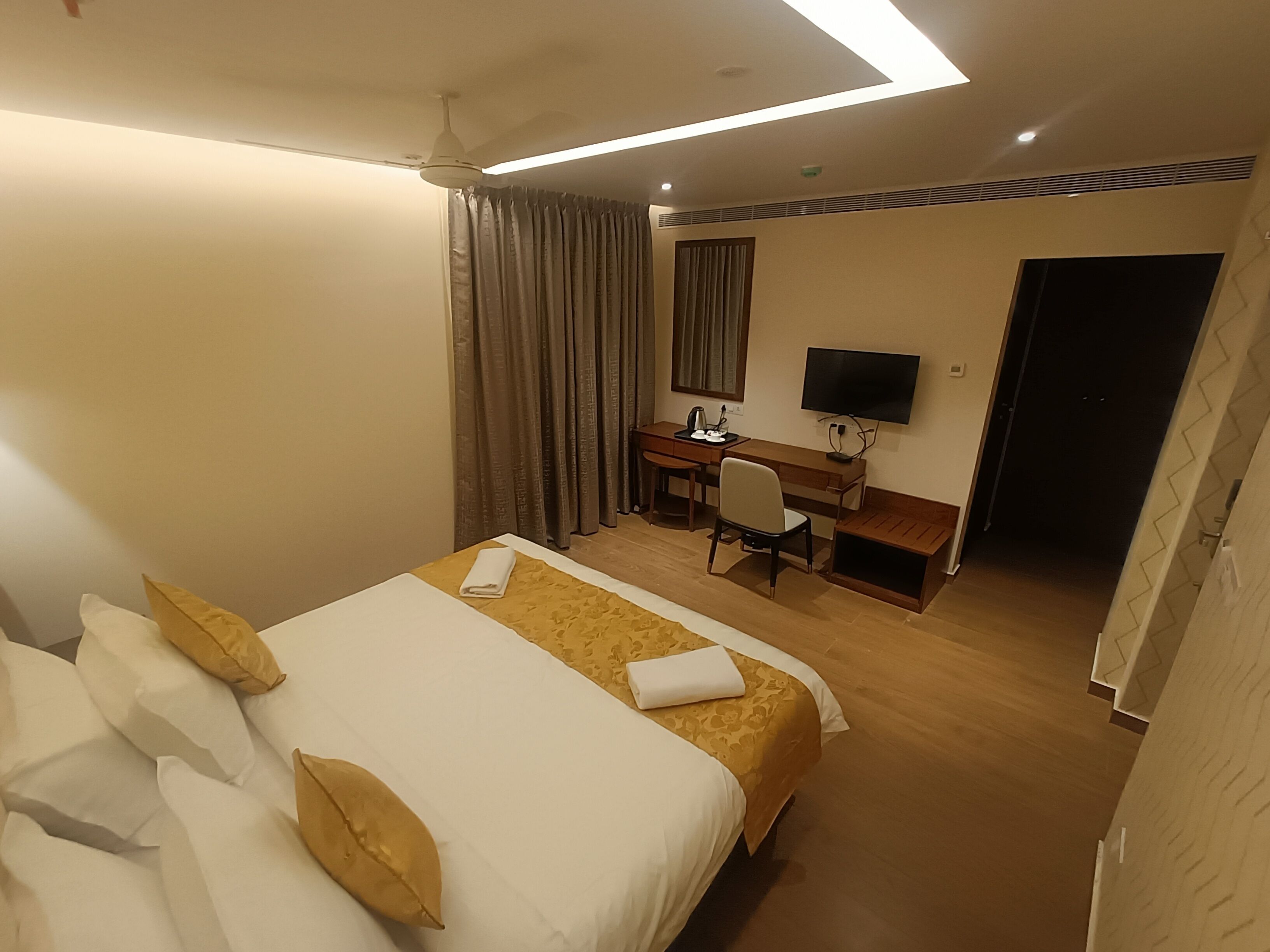 Una habitación de hotel con cama, escritorio, silla, televisor y puerta.