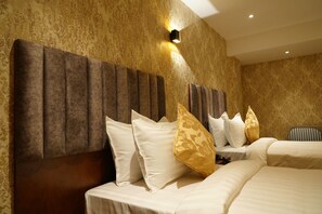 Une chambre d’hôtel avec un grand lit, plusieurs oreillers, une tête de lit et un luminaire fixé au mur.