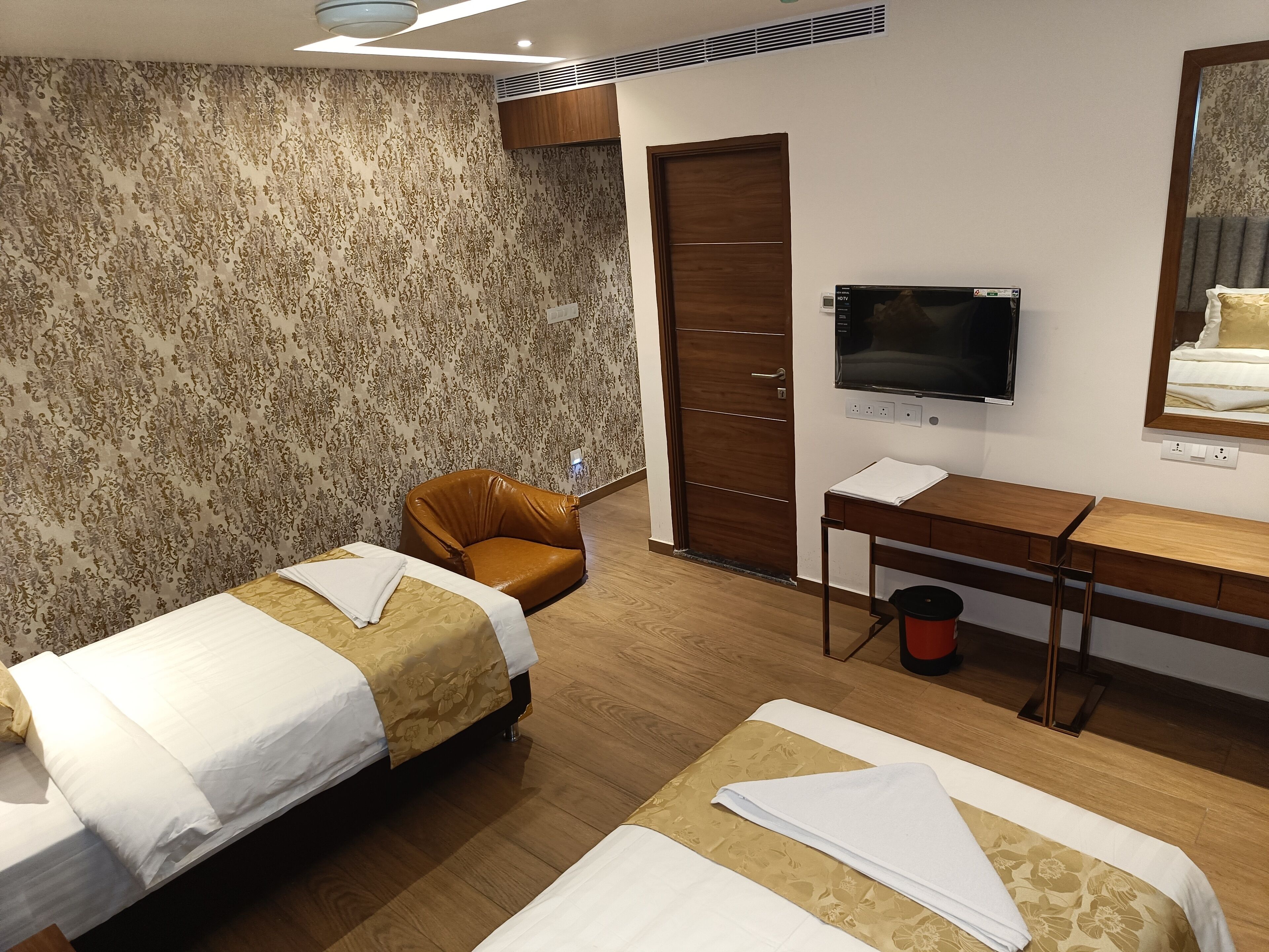 Une chambre d’hôtel avec deux lits, un bureau, une télévision et une armoire.