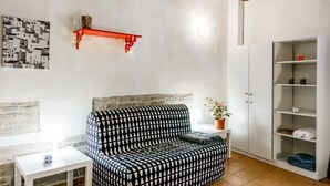 A living room with a patterned sofa, a white cabinet, and a red shelf. - Studio located on the ground floor of a building from 1900.In 35 square meters of space it accommodates up two people with a double sofa bed.In a quiet and residential location, right in the center.We are located within the ZTL (limited traffic area).Con (Parma)