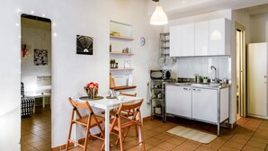 A compact kitchen with white cabinets, a microwave, and a sink. There is a dining table with chairs and a small island with a vase of flowers. - Studio located on the ground floor of a building from 1900.In 35 square meters of space it accommodates up two people with a double sofa bed.In a quiet and residential location, right in the center.We are located within the ZTL (limited traffic area).Con (Parma)