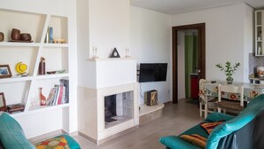 Una sala de estar con chimenea, televisor y comedor con mesa y sillas.