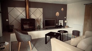 Un salon moderne avec une cheminée, un canapé, un téléviseur et une petite table.
