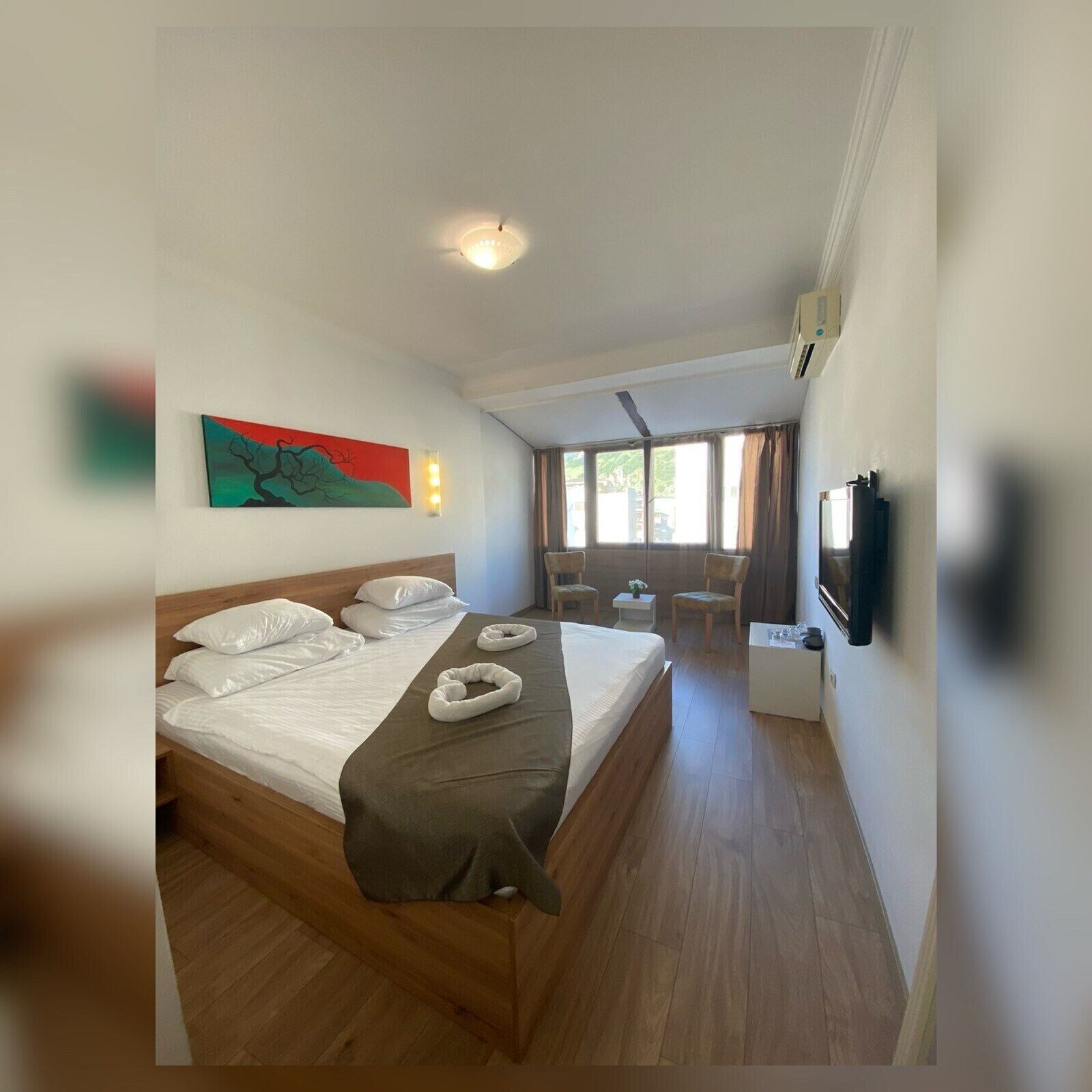 Habitación de hotel con una cama grande, un escritorio, una silla y un televisor montado en la pared.