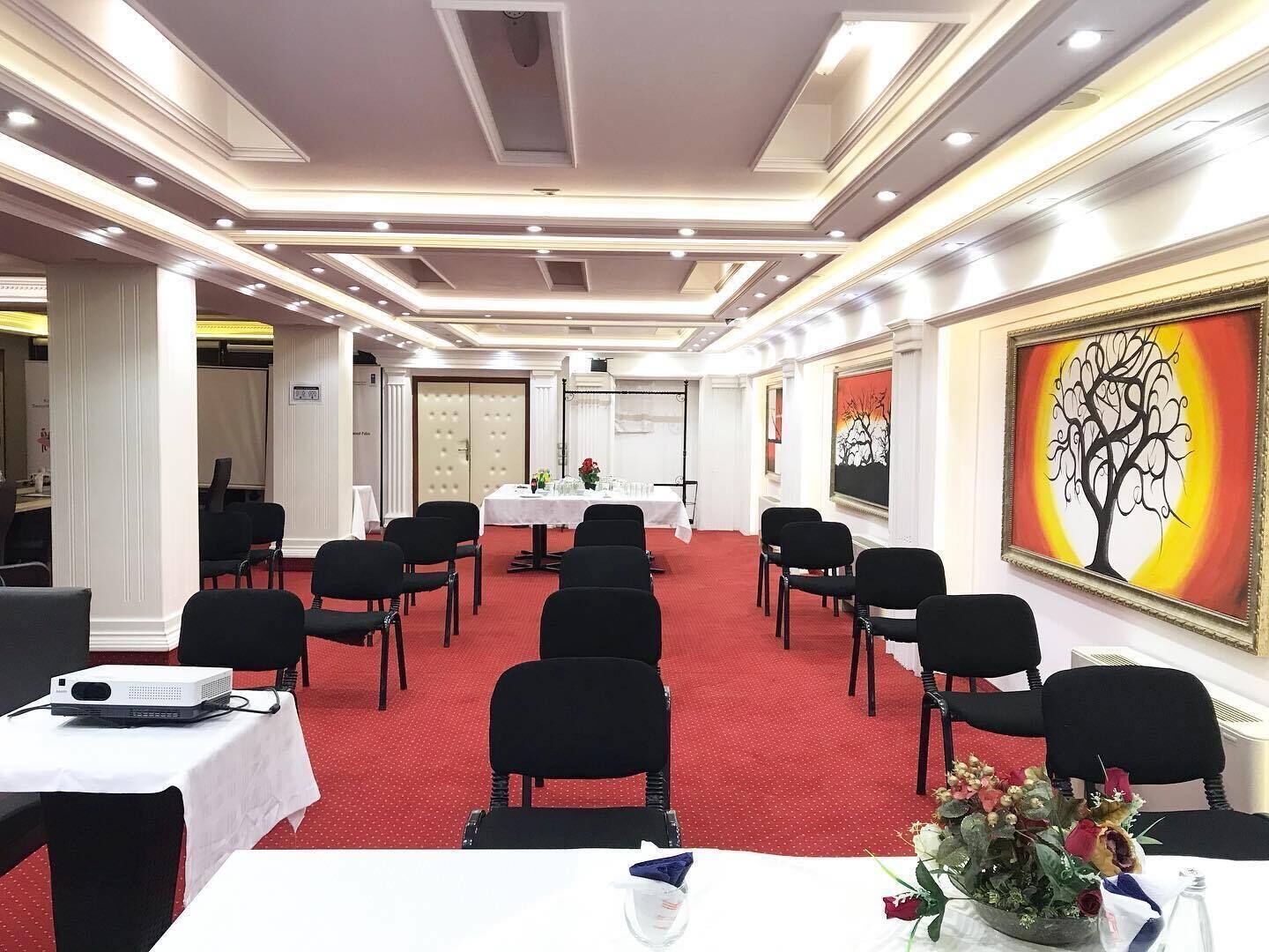 Una sala conferenze con tavoli, sedie e un proiettore.