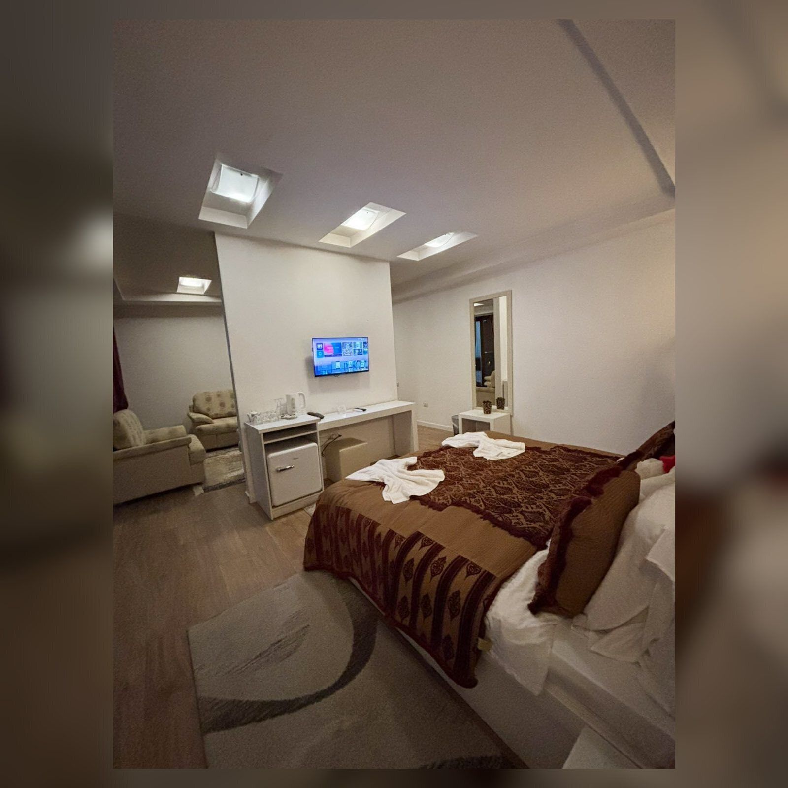 Habitació d'hotel amb llit, escriptori, cadira, televisió i mirall.