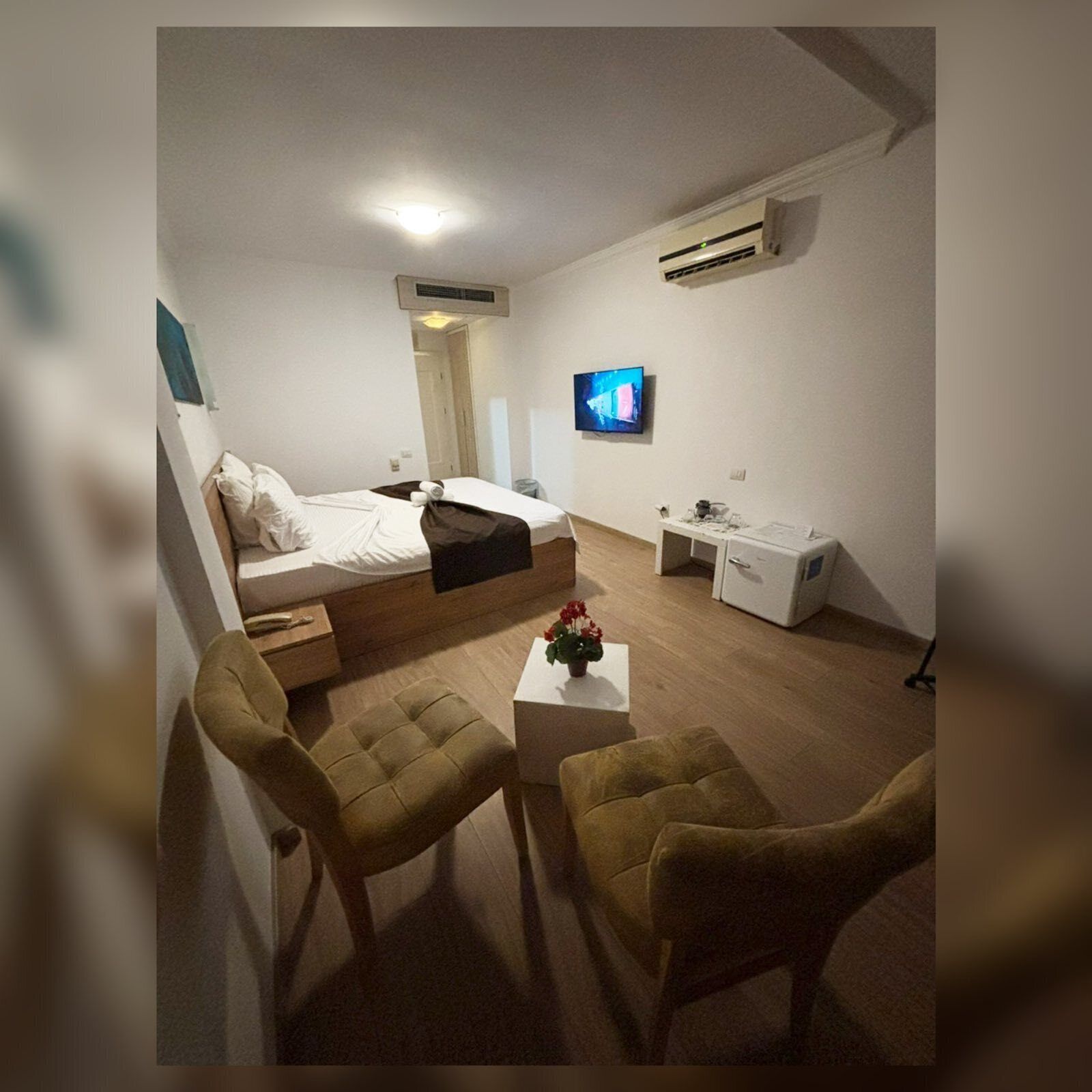 Ein kleines Hotelzimmer mit einem Bett, einem Schreibtisch, einem Fernseher und zwei Stühlen.