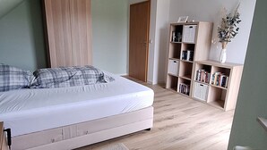 A bedroom with a bed, a bookshelf, a radiator, and a door. - Large rural vacation home in a quiet location near the Spreewald (Dahme/Mark)