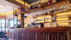 Zona de bar con mostrador de madera, botellas de vino y copas colgantes.