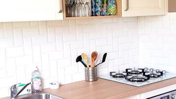 Een moderne keuken met witte kasten, een roestvrijstalen spoelbak, een vaatwasser, een fornuis en een betegelde achterwand.