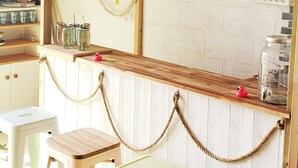A bar area with a wooden counter, two stools, a hammock, and a 'COCKTAIL' sign. - Unlimited private indoor Jacuzzi at Mont saint-michel (Pontorson)