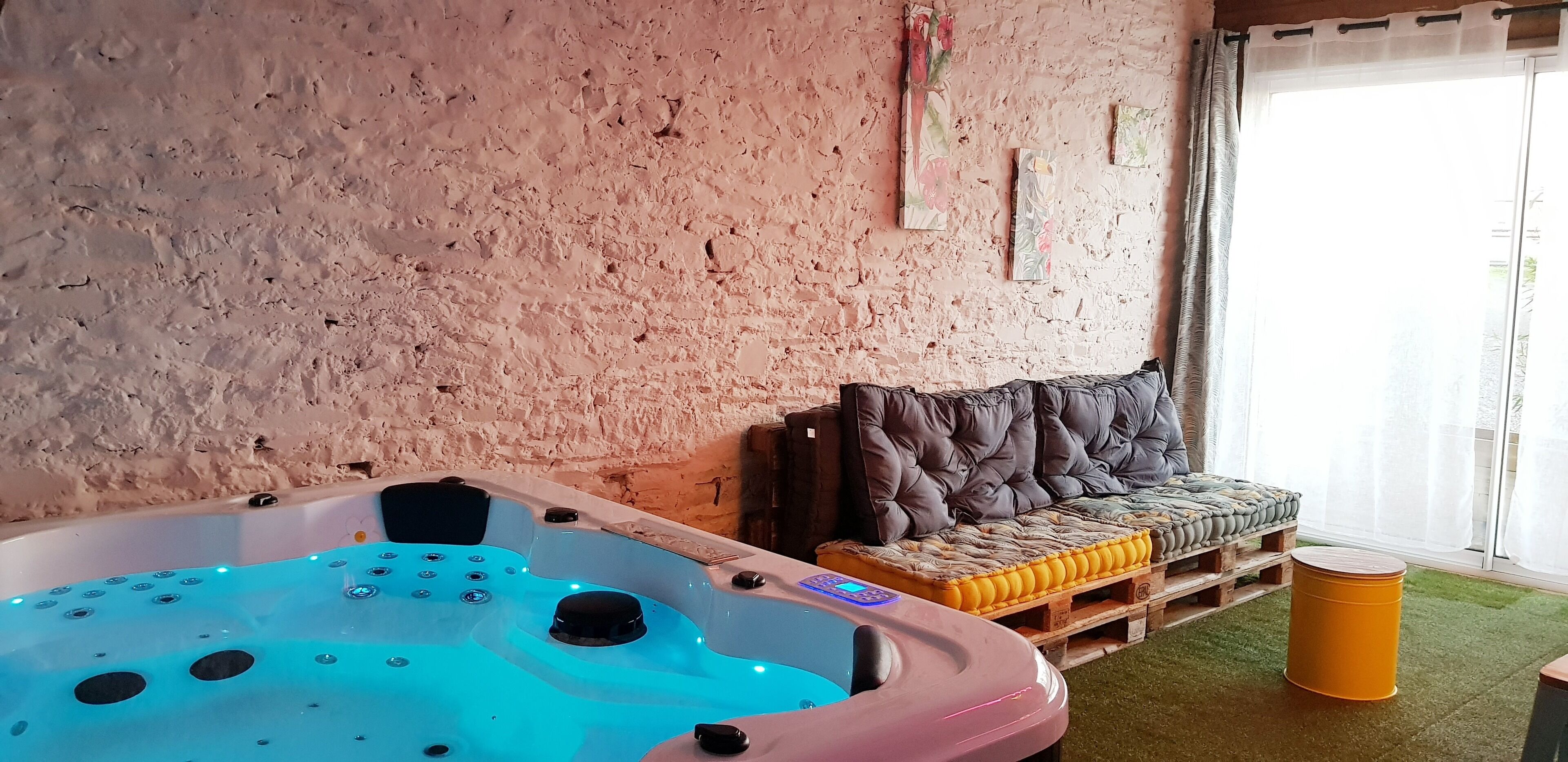 Ett spaområde med en bubbelpool, en bekväm sittgrupp och en träpall med kuddar.