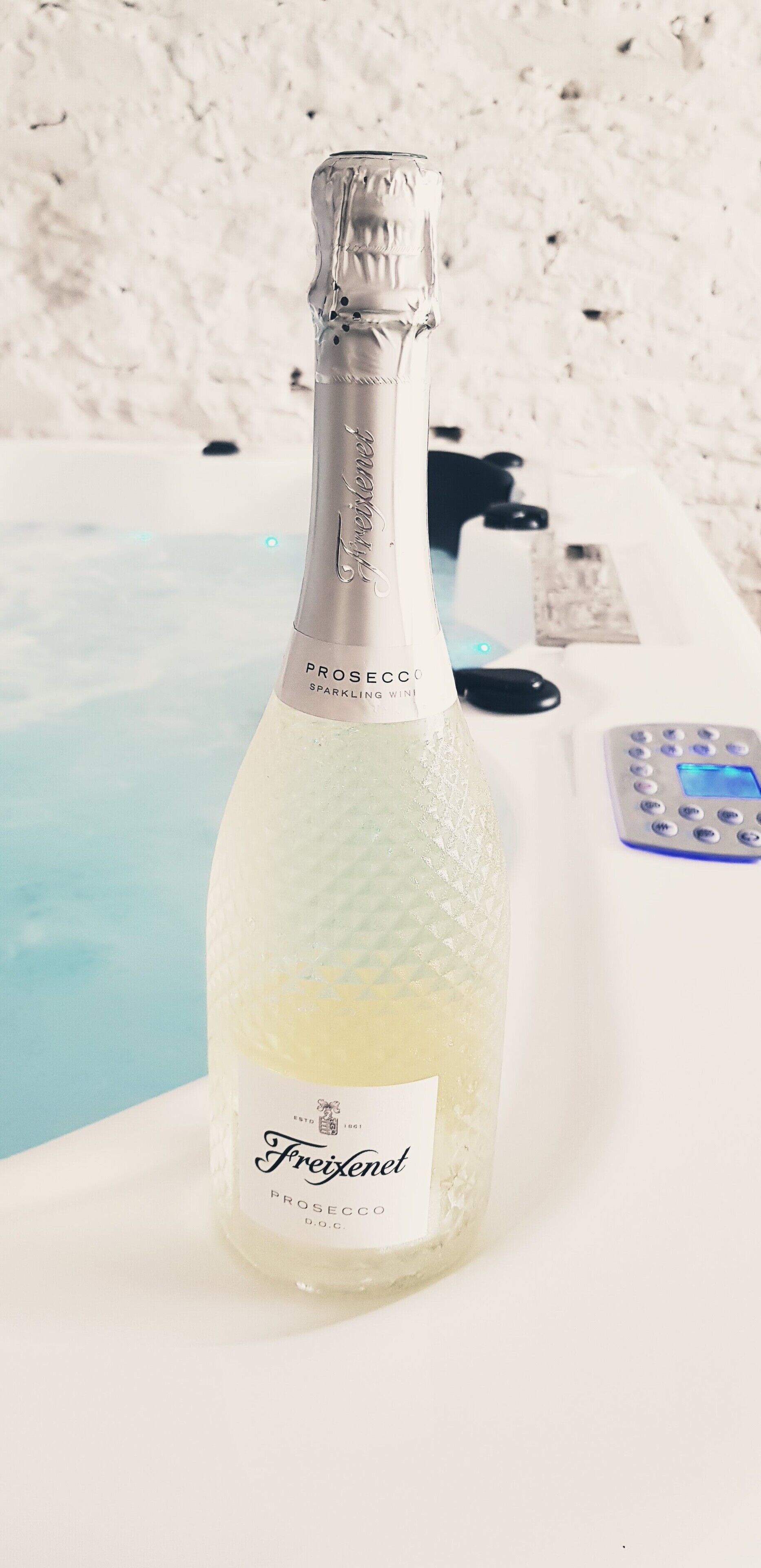 A bottle of Freixenet Prosecco sparkling wine next to a pool.