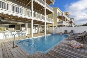 Et poolområde med træterrasse, liggestole og en pool med metalstige.